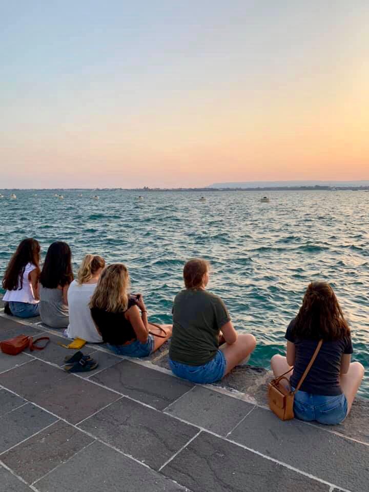 Students watching the sunset over the water at the Ortigia marina, Siracusa